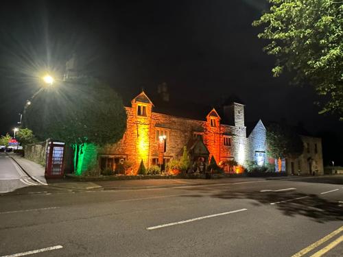 an old building with lights on a street at night at The Old Manor House Hotel in Keynsham