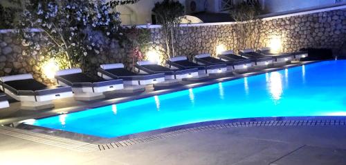 a swimming pool with a bunch of chairs in it at Sellada Beach in Perissa