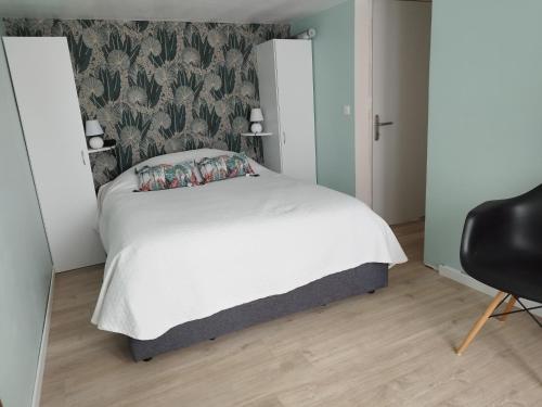 une chambre avec un lit blanc et une chaise dans l'établissement Hortensia, à Grandcamp-Maisy