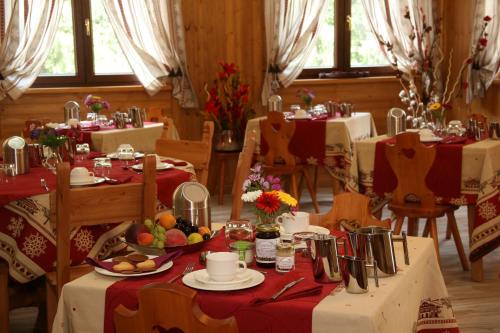 a dining room with tables with red and white table cloth at Hotel Boton D'Or & Wellness in La Thuile