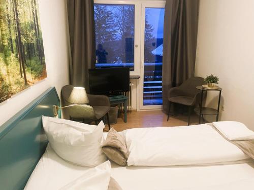 a bedroom with a bed and a desk and a television at Berghotel HARZ in Hahnenklee-Bockswiese