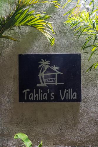 a sign on the side of a building with palm trees at Tahlia's Villa in Sorongjukung