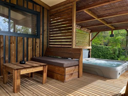 eine Sauna mit einem Whirlpool auf einer Holzterrasse in der Unterkunft Domaine du Hygge Chalets Lodges & Spa in Anould