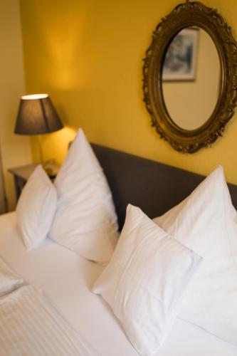 a bedroom with a bed with white pillows and a mirror at RATSKELLER Hotel & Restaurant in Kröv