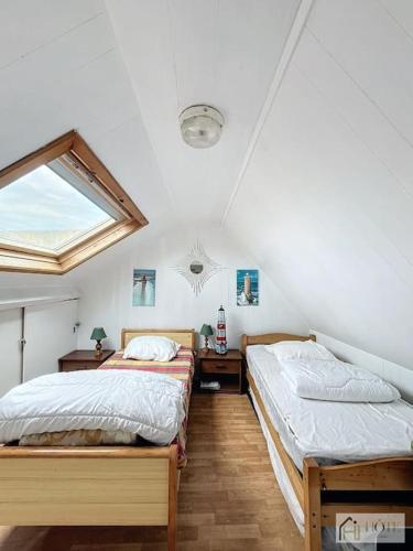 deux lits dans une chambre avec une fenêtre dans l'établissement Appartement place Rubben - 2 pas de la Mer, à Bray-Dunes