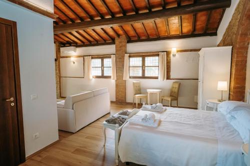 a bedroom with a large white bed and a couch at Borgo Il Poggiaccio Residenza d'Epoca in Sovicille