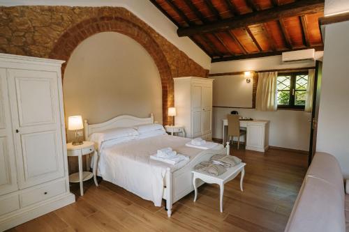a bedroom with a white bed and a table at Borgo Il Poggiaccio Residenza d'Epoca in Sovicille