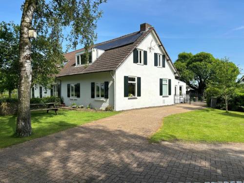 uma casa branca com uma árvore e uma entrada em De Hazeldonck em Gemert