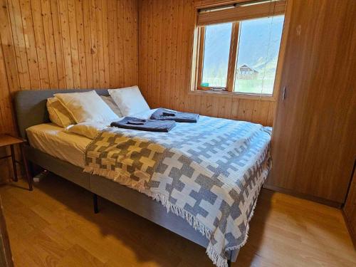 a bedroom with a bed with a blanket and a window at Cozy Cabin near Golden Circle - Private Hot Tub in Kotströnd