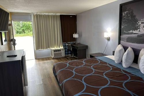 フローレンスにあるTravelodge by Wyndham Florenceの大きなベッドとデスクが備わるホテルルームです。