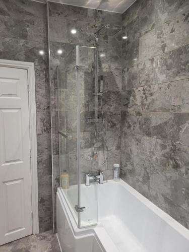 uma casa de banho com um chuveiro e uma banheira em A Quiet & Comfortable 4 Bedroom house em Manchester