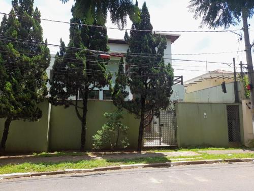 a house with a green fence and trees at Mansão Adalgisa in Osasco
