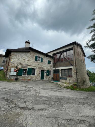 an old stone building with green doors and a window at La Corte dei Celti La fonte in San Benedetto Del Querceto