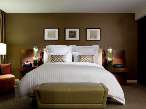 a bedroom with a large white bed and a chair at Pullman Sydney Olympic Park in Sydney