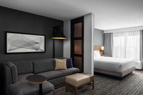 Hyatt Place San Antonio Riverwalk في سان انطونيو: غرفة في الفندق مع أريكة وسرير