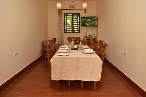 una sala da pranzo con tavolo e sedie bianchi di The Little Home ad Arusha