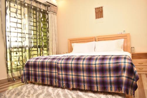 a bedroom with a bed with a plaid blanket at The Little Home in Arusha