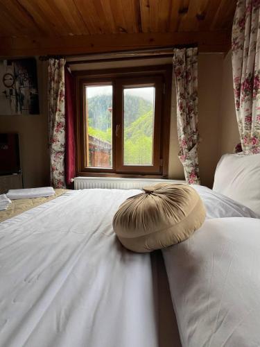 a large white bed with a pillow on it with a window at Ayder Paradise Otel in Ayder Yaylasi