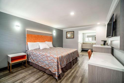 a hotel room with a bed and a television at Travelodge Inn & Suites by Wyndham Bell Los Angeles Area in Bell