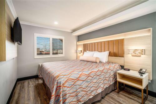 a hotel room with a bed and a window at Travelodge Inn & Suites by Wyndham Bell Los Angeles Area in Bell