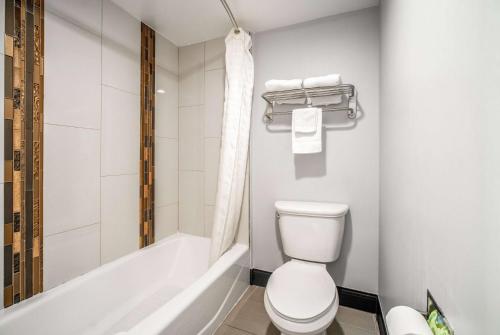 a bathroom with a toilet and a bath tub at Travelodge Inn & Suites by Wyndham Bell Los Angeles Area in Bell