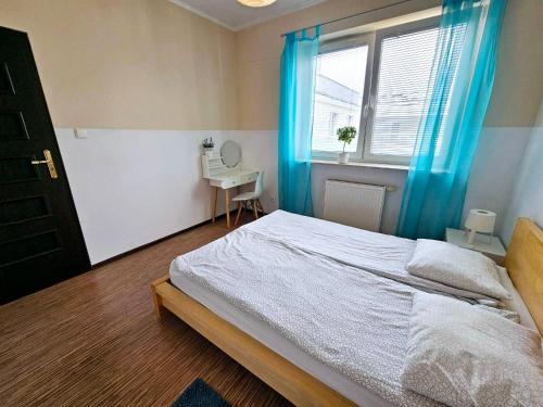 a bedroom with a bed with blue curtains and a window at Fresh Green Kabaty apartment 4 in Warsaw