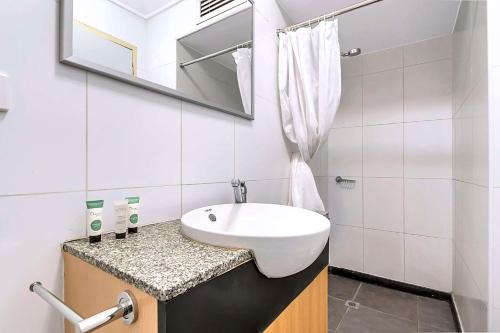 ein weißes Badezimmer mit einem Waschbecken und einem Spiegel in der Unterkunft Econo Lodge Karratha in Karratha