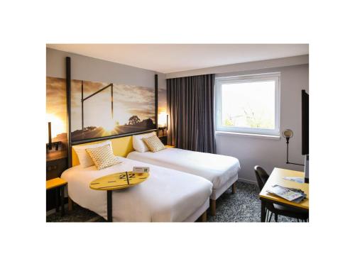クレルモン・フェランにあるIbis Styles Clermont-Ferrand Républiqueのベッド2台とテーブルが備わるホテルルームです。