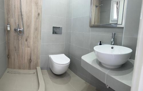 uma casa de banho com um lavatório branco e um WC. em Melina Hotel em Fira