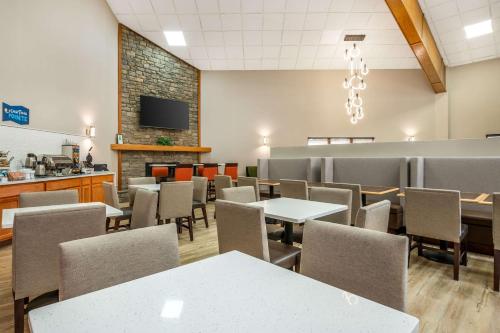 Clarion Pointe Louisville East في لويزفيل: غرفة طعام مع طاولات وكراسي وتلفزيون