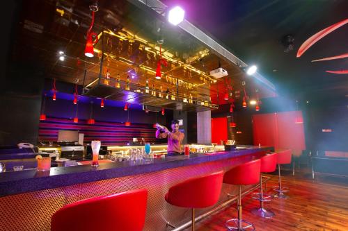 a person standing at a bar in a room with red chairs at Gokulam Park Coimbatore in Coimbatore