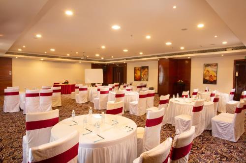 a banquet hall with white tables and white chairs at Gokulam Park Coimbatore in Coimbatore