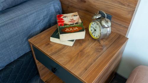 a book and an alarm clock on a bedside table at ELEGANCE SİRİUS in Kayseri