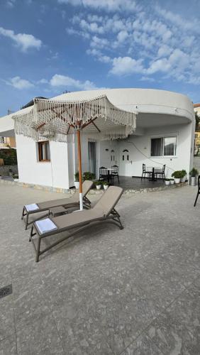 un patio con sillas y sombrilla y un edificio en Vila Malo 2, en Ksamil