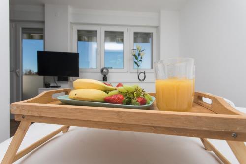 a tray with a plate of fruit and a glass of orange juice at Makaria in Split