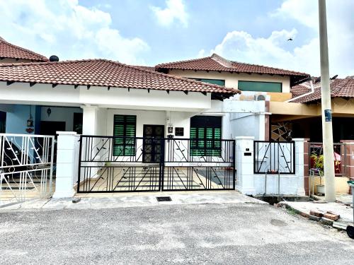uma casa com um portão em frente em The Amore Homestay Klebang, Melaka em Malaca