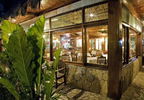 un ristorante con finestre, tavolo e sedie di Hotel Jaguar Inn Tikal a Tikal