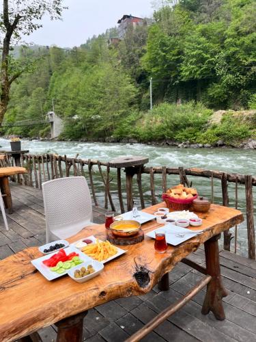 a wooden table with food on it next to a river at Yaşam Bungalows Otel in Çamlıhemşin