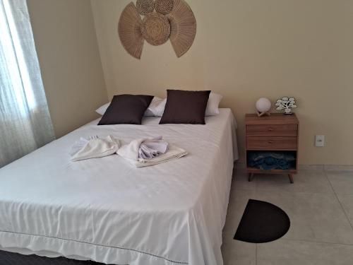 a bedroom with a white bed with two towels on it at Casa vila costeira. in Camocim
