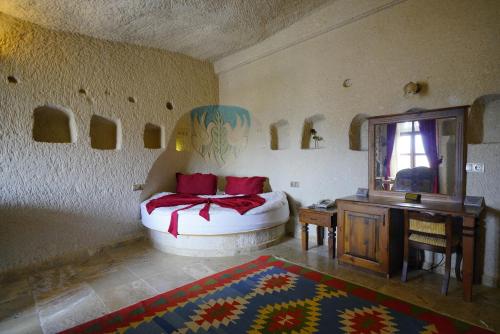 a bedroom with a bed and a table and a mirror at Vezir Cave Suites in Goreme