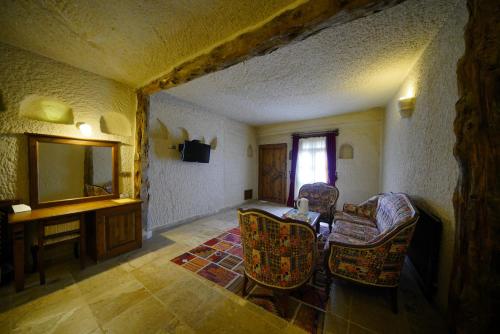 a living room with chairs and a table and a mirror at Vezir Cave Suites in Goreme