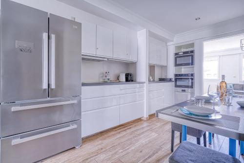 une cuisine avec des armoires blanches et un réfrigérateur en acier inoxydable dans l'établissement Le Marignan, à Cannes