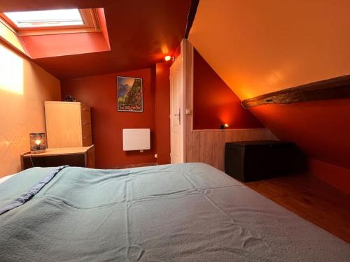 - une chambre avec des murs orange et un grand lit dans l'établissement Charme et Calme au Cœur de ville, à Moret-sur-Loing