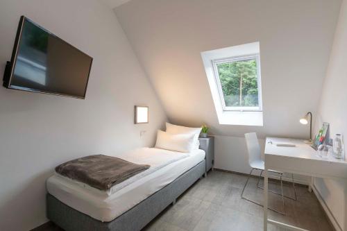 Schlafzimmer mit einem Bett, einem Schreibtisch und einem TV in der Unterkunft Waldhotel Brand's Busch in Bielefeld