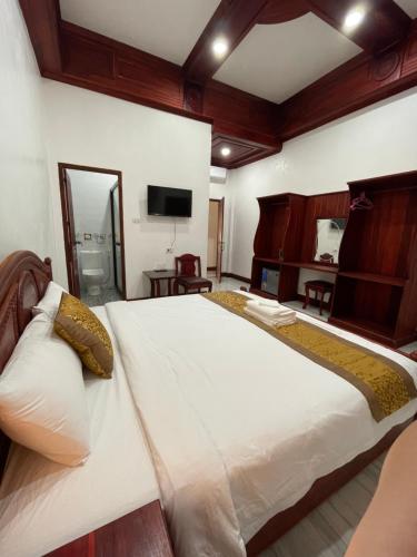 een slaapkamer met een groot wit bed en een televisie bij PhaiLin Hotel in Luang Prabang