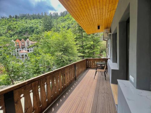 a balcony with a wooden deck with a table and chairs at Greenwood in Borjomi