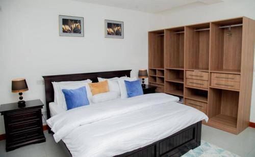 カンパラにあるLuxury Cozy Kampala Apartment with 2 Bedroomsの大きなベッドと木製のキャビネットを備えた寝室