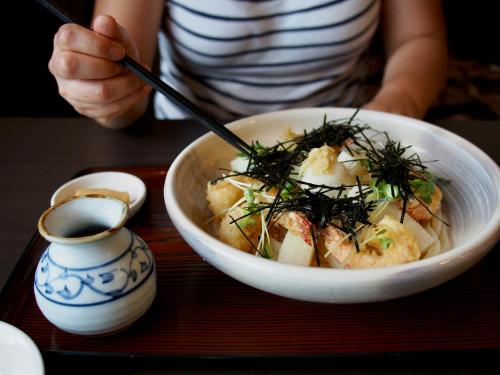 a person holding a bowl of food on a tray at The Maples Niseko in Niseko