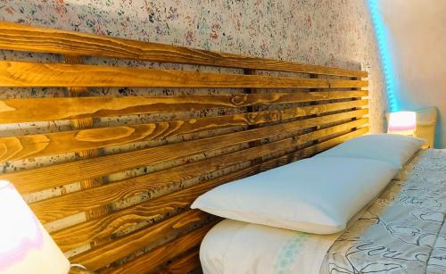 a bed with a wooden headboard in a room at L'ombelico del Monte - appartamenti in centro storico in Piazza Armerina