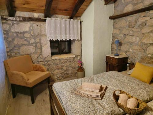 1 dormitorio con cama, silla y pared de piedra en Kuća za odmor Ameli, en Mošćenička Draga